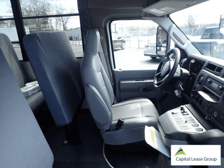 Driver area and front passenger seating inside a 12-passenger school activity bus.
