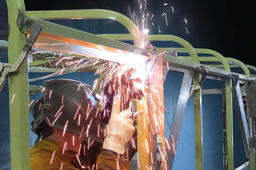 Magellan school activity bus tubular steel cage being welded during manufacturing