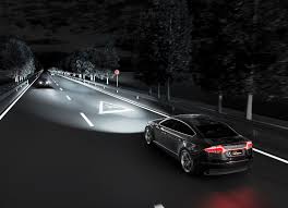vehicle on dark road with headlights illuminating path