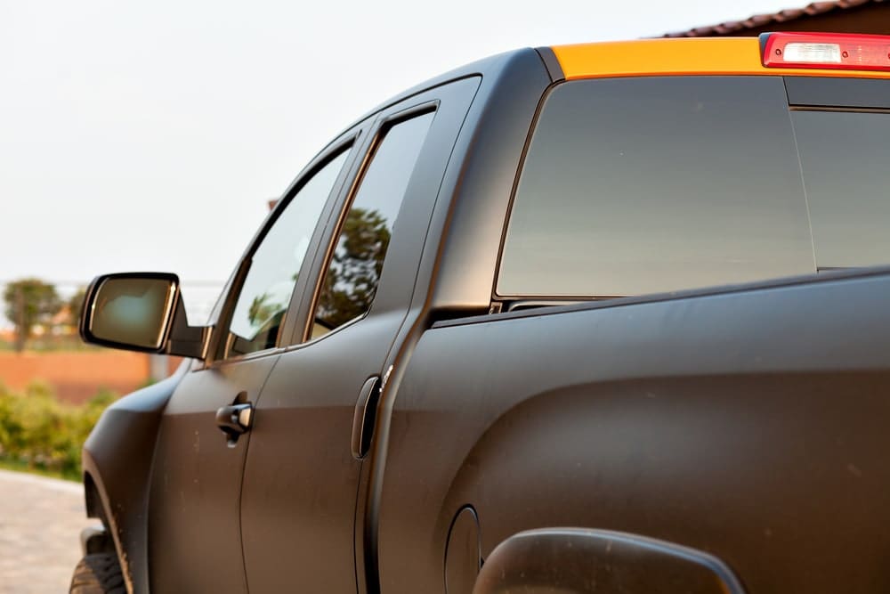 zoomed in rear angle view of back and side of black pickup truck